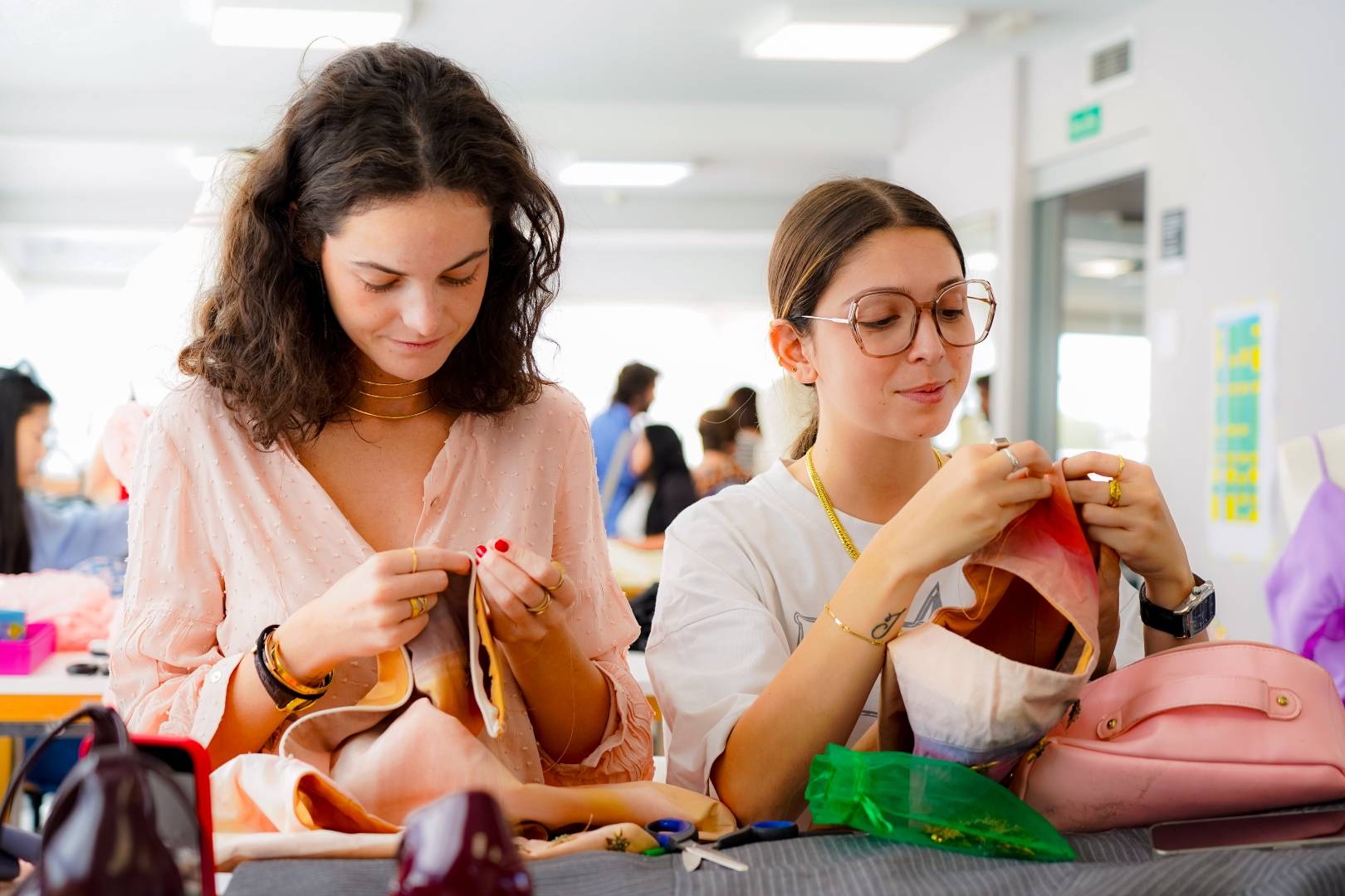 Dos mujeres trabajaban en un proyecto de costura en un aula luminosa y creativa.