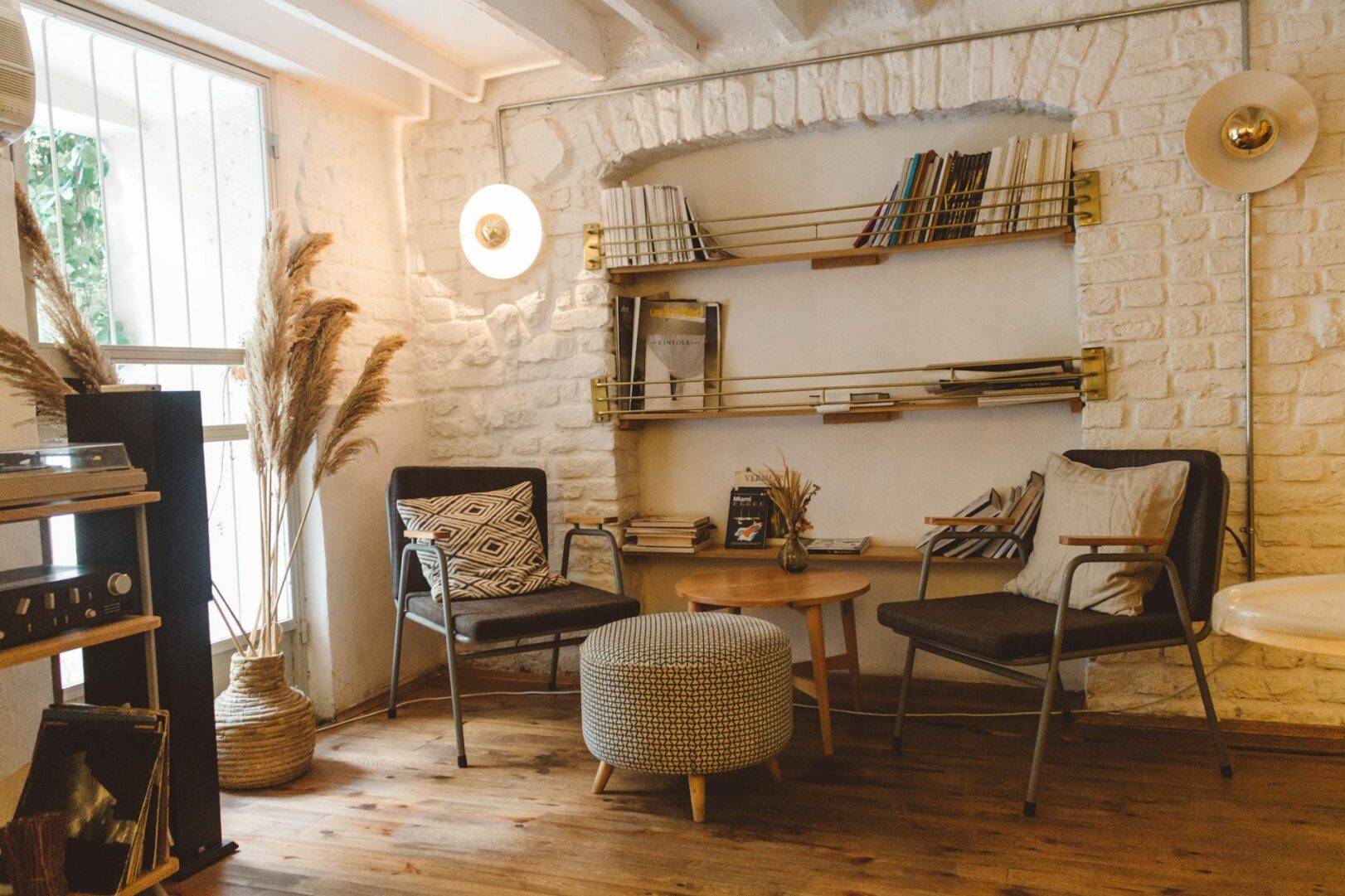 Una sala de estar acogedora con sillas cómodas, una mesa central y estanterías llenas de libros.