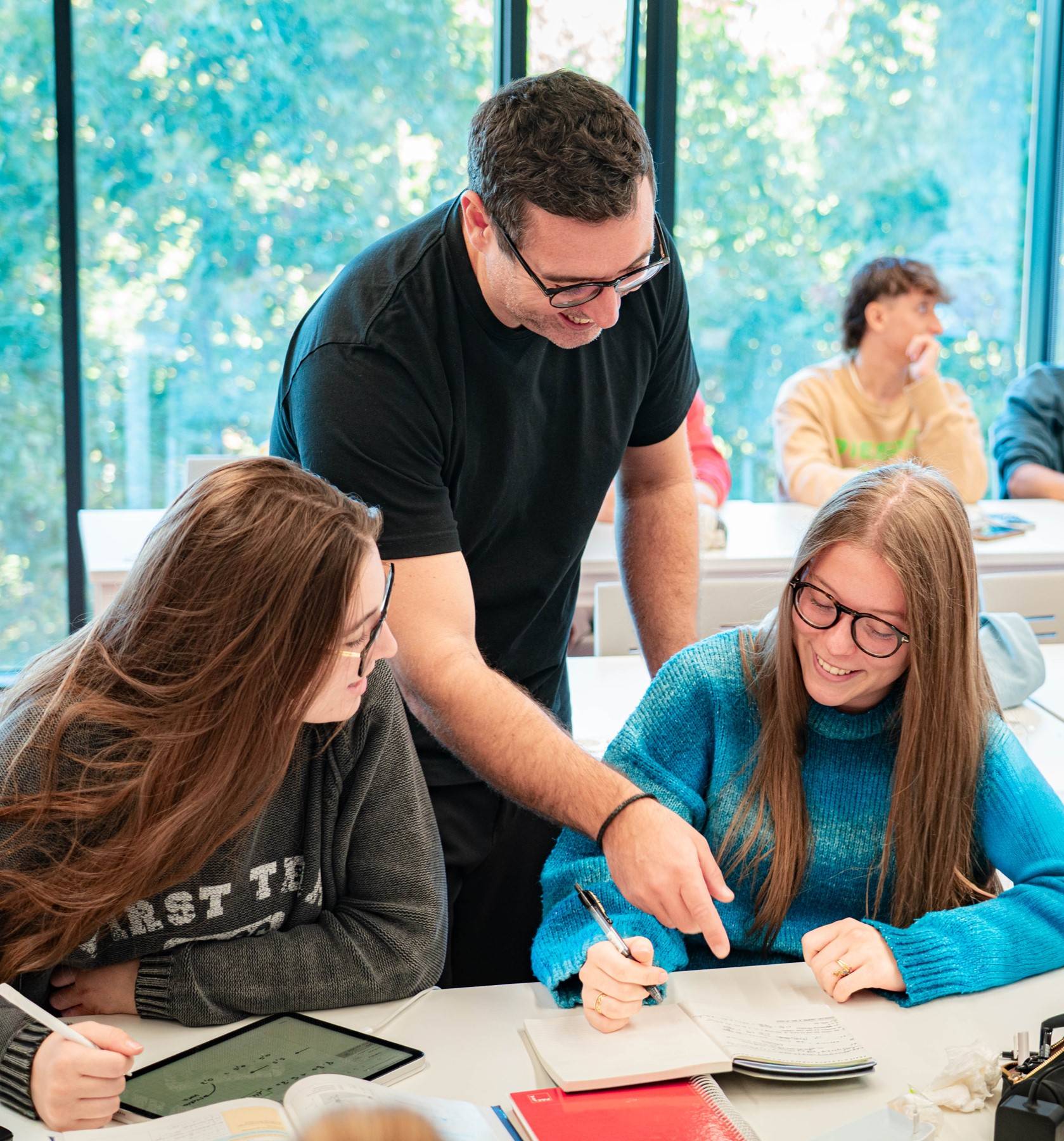 Un profesor enseña a dos estudiantes en un aula moderna.