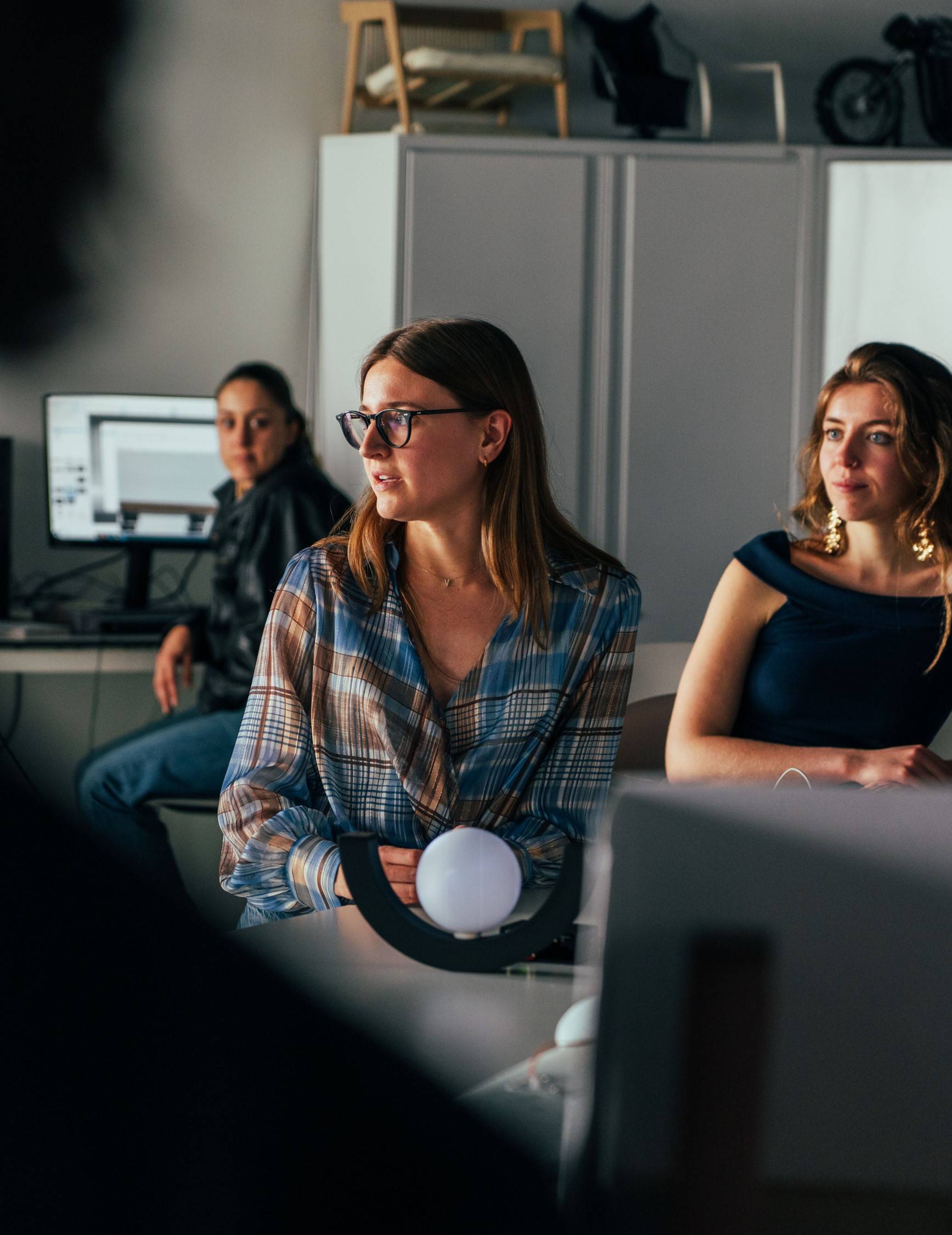 Un grupo de mujeres sentadas en un ambiente de oficina, escuchando atentamente durante una reunión.