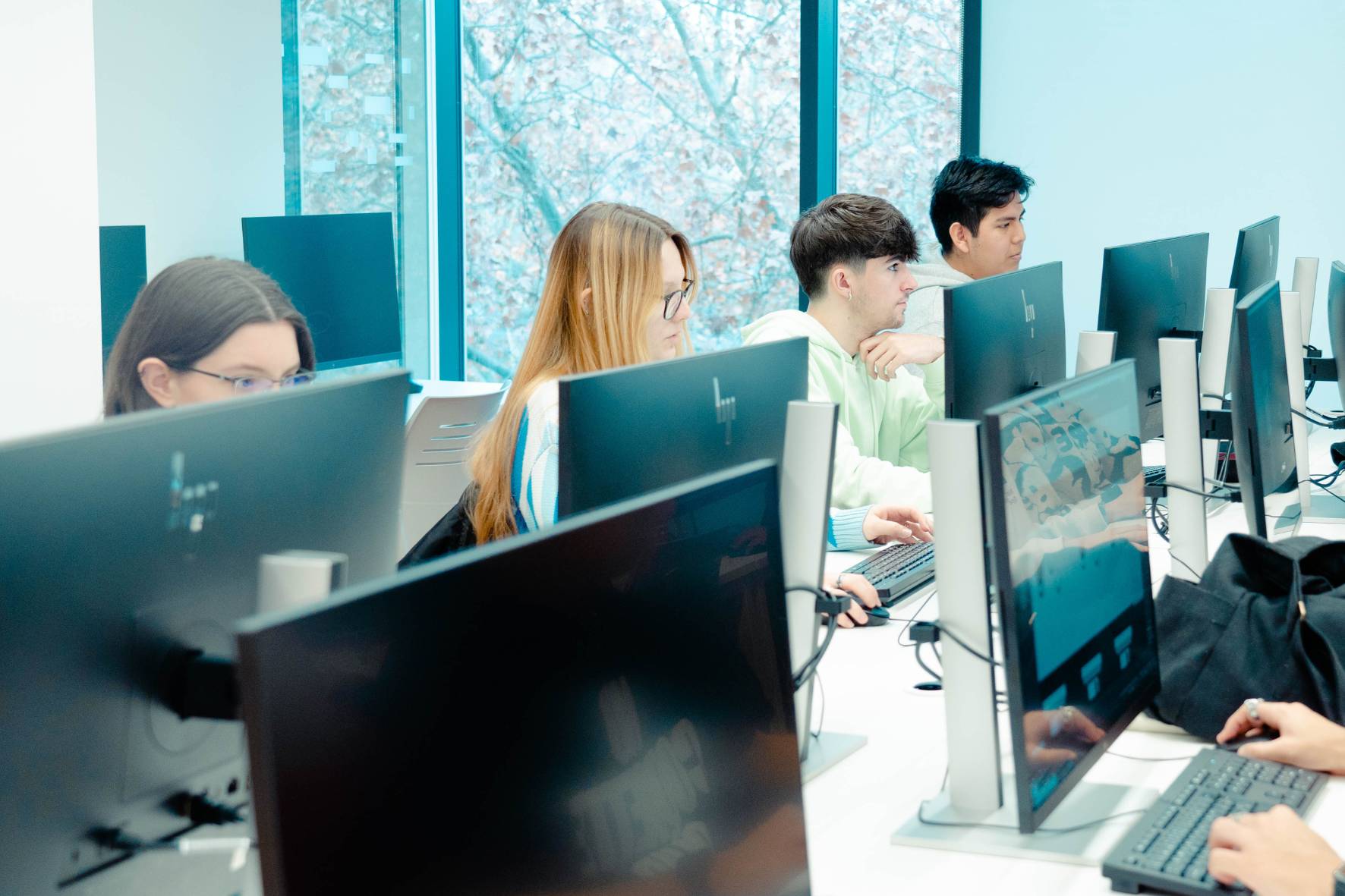 Un grupo de estudiantes trabajando en computadoras en un entorno moderno.