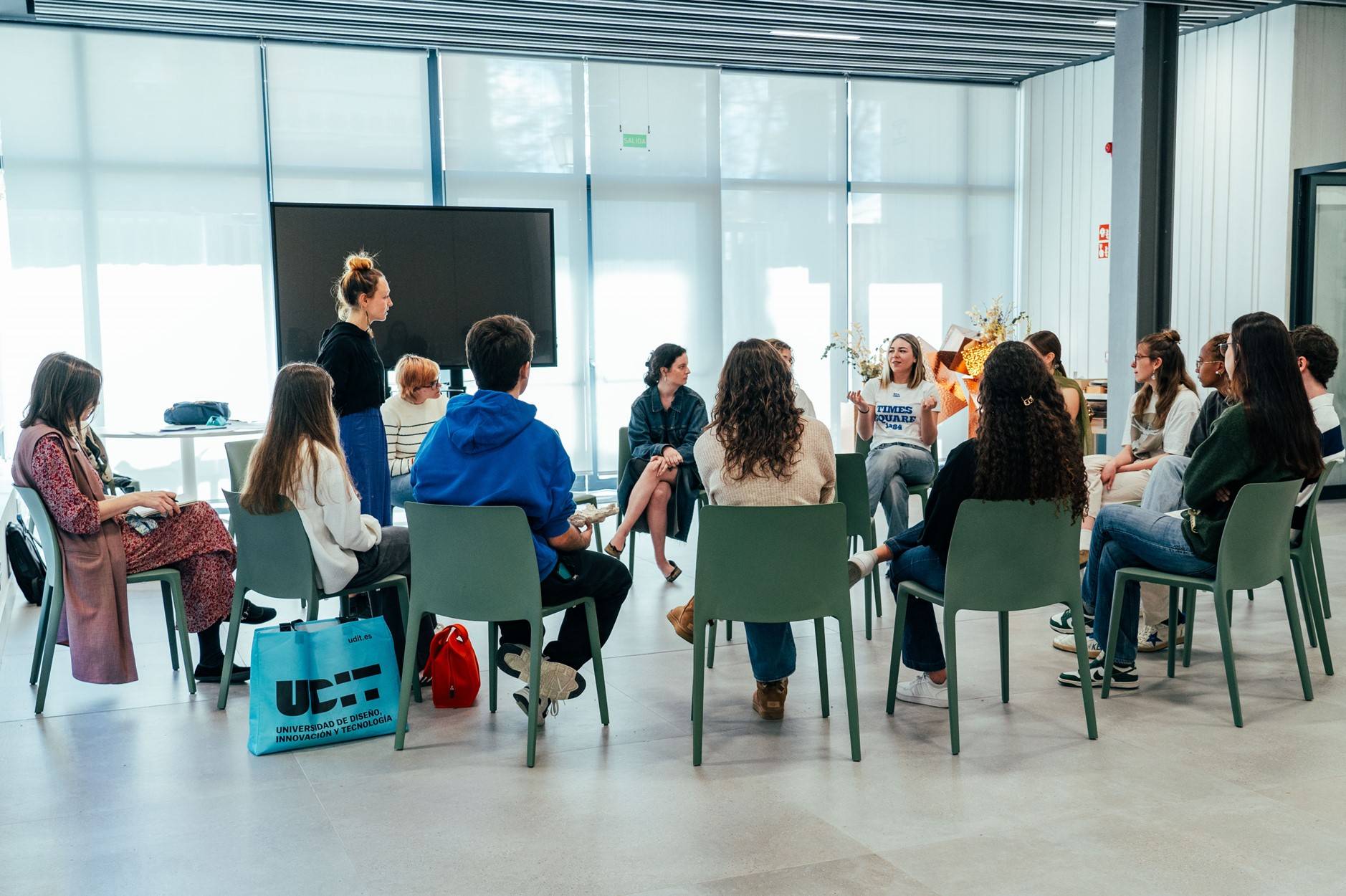Un grupo de jóvenes participando en una dinámica de grupo en un salón moderno.