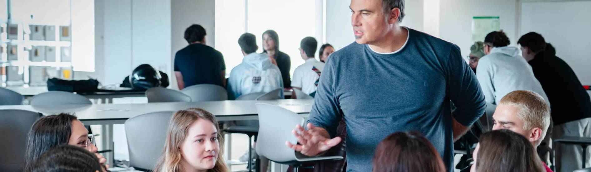 Un profesor se dirige a un grupo de estudiantes en un aula moderna.