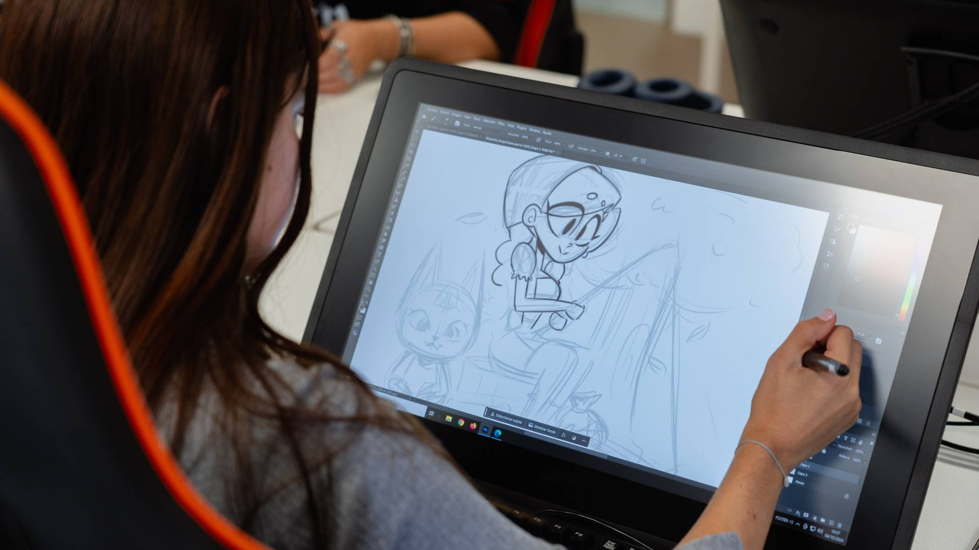 Una persona está dibujando en una pantalla digital en un entorno creativo.