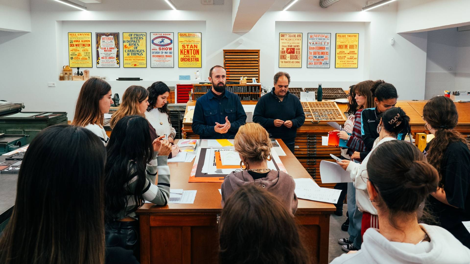 Un grupo de personas participa en un taller creativo en un espacio que parece ser un estudio de diseño o tipografía.