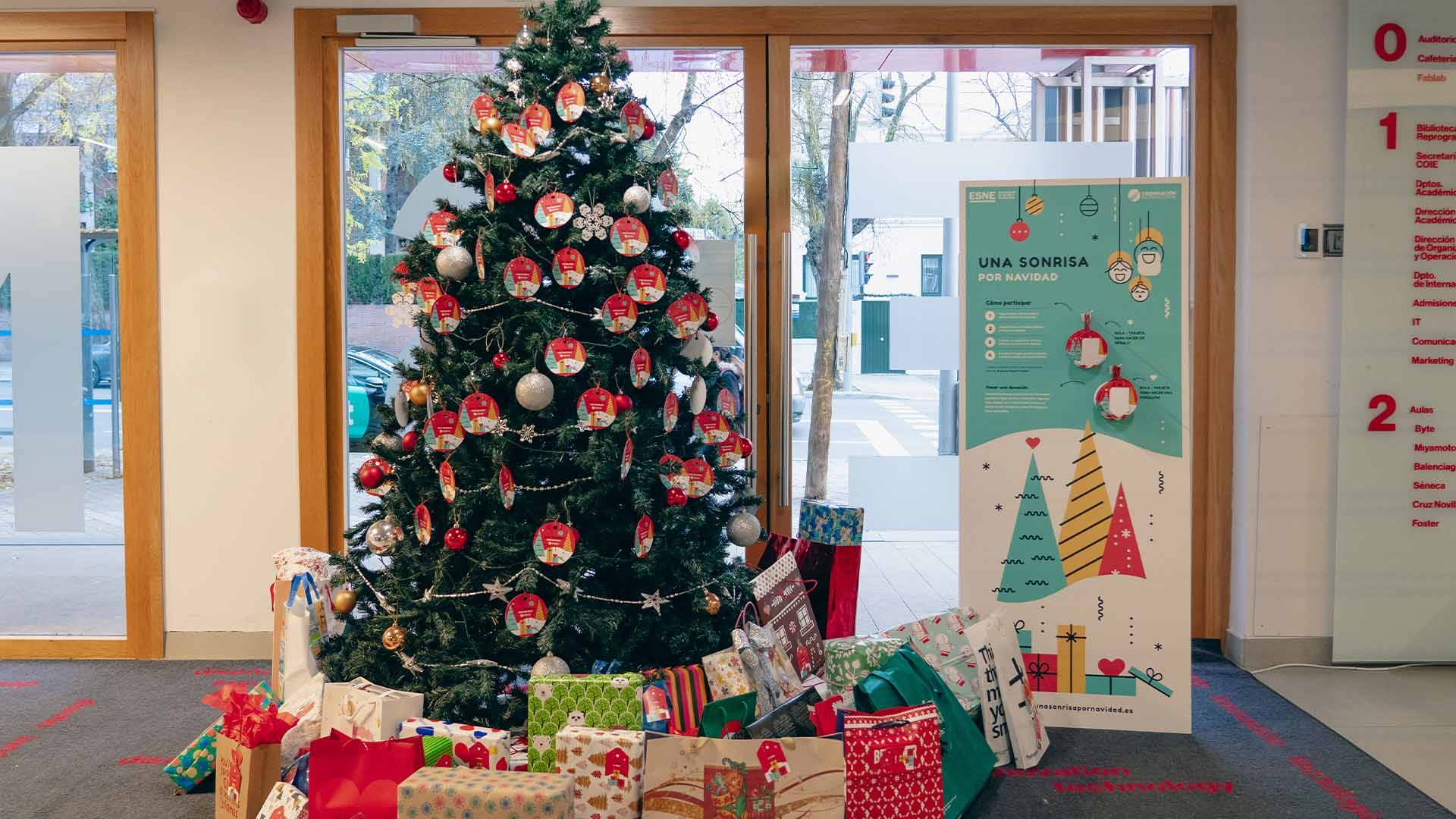 Un árbol de Navidad decorado rodeado de regalos y una cartelera navideña.