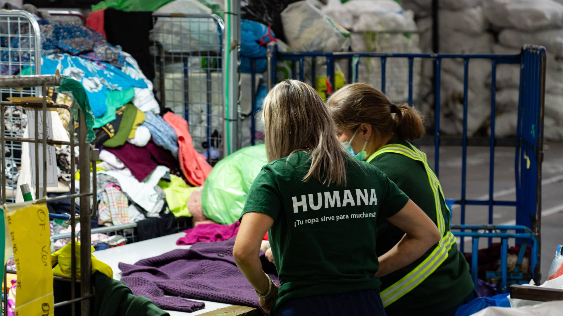 Dos personas organizan ropa en un centro de reciclaje.