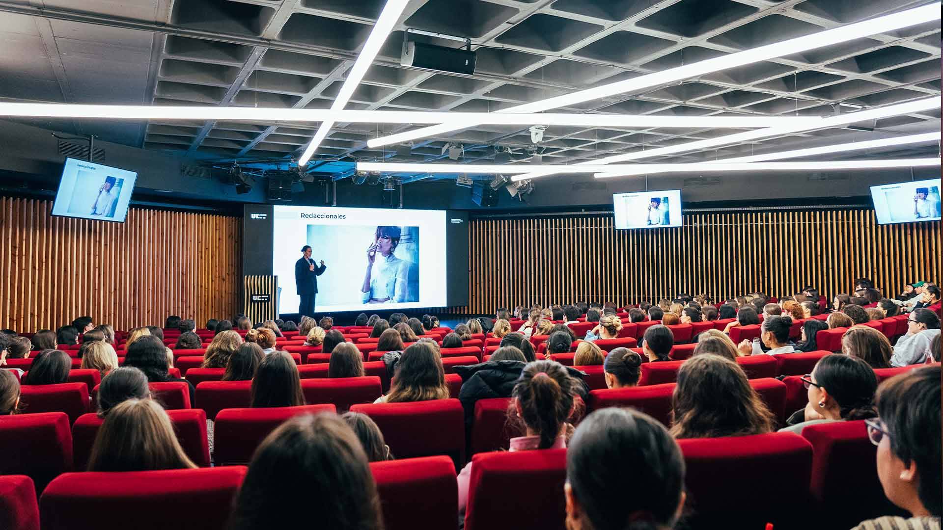 Una conferencia ante un gran público sentado en un auditorio moderno.