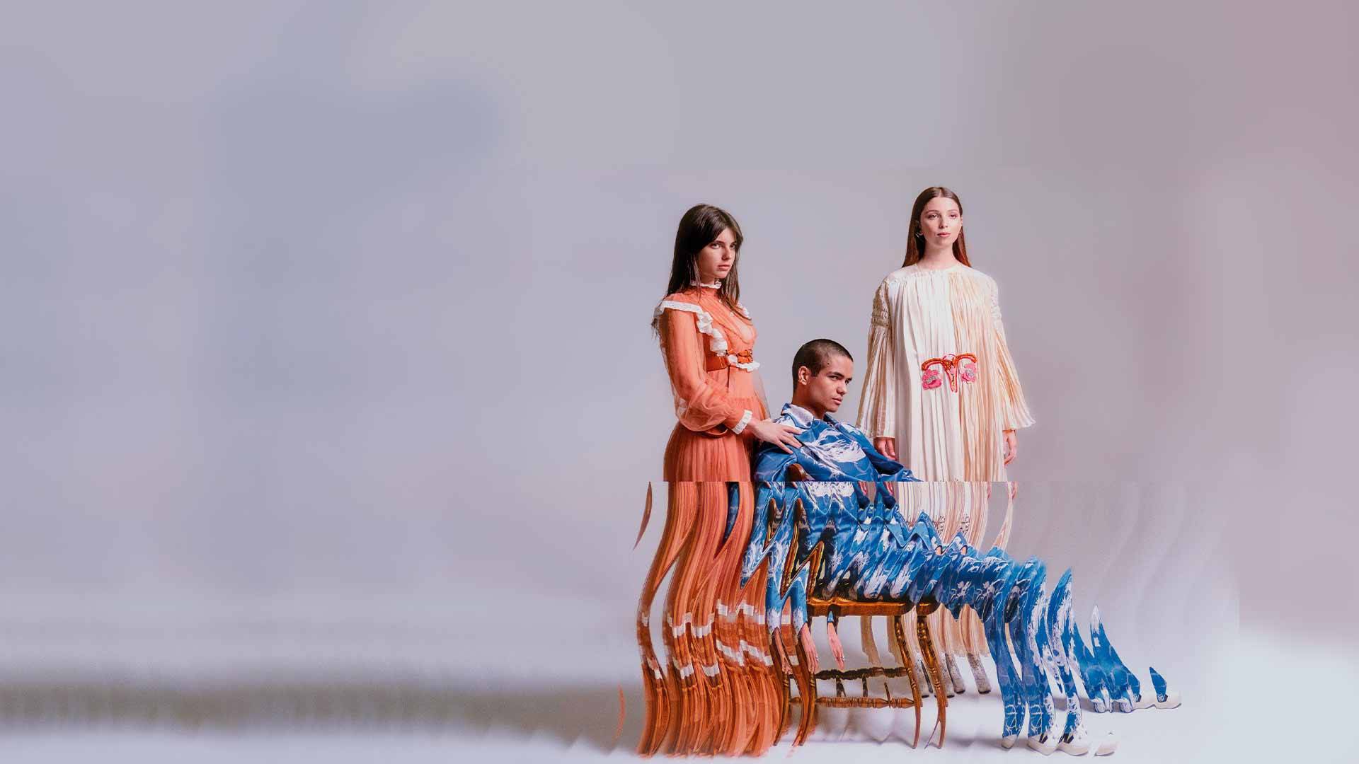 La imagen muestra a tres modelos posando en un entorno artístico con un efecto de distorsión visual.