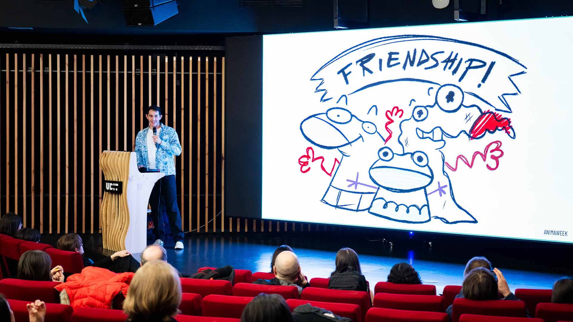 Un presentador habla sobre la amistad mientras se proyecta una ilustración divertida en una pantalla.