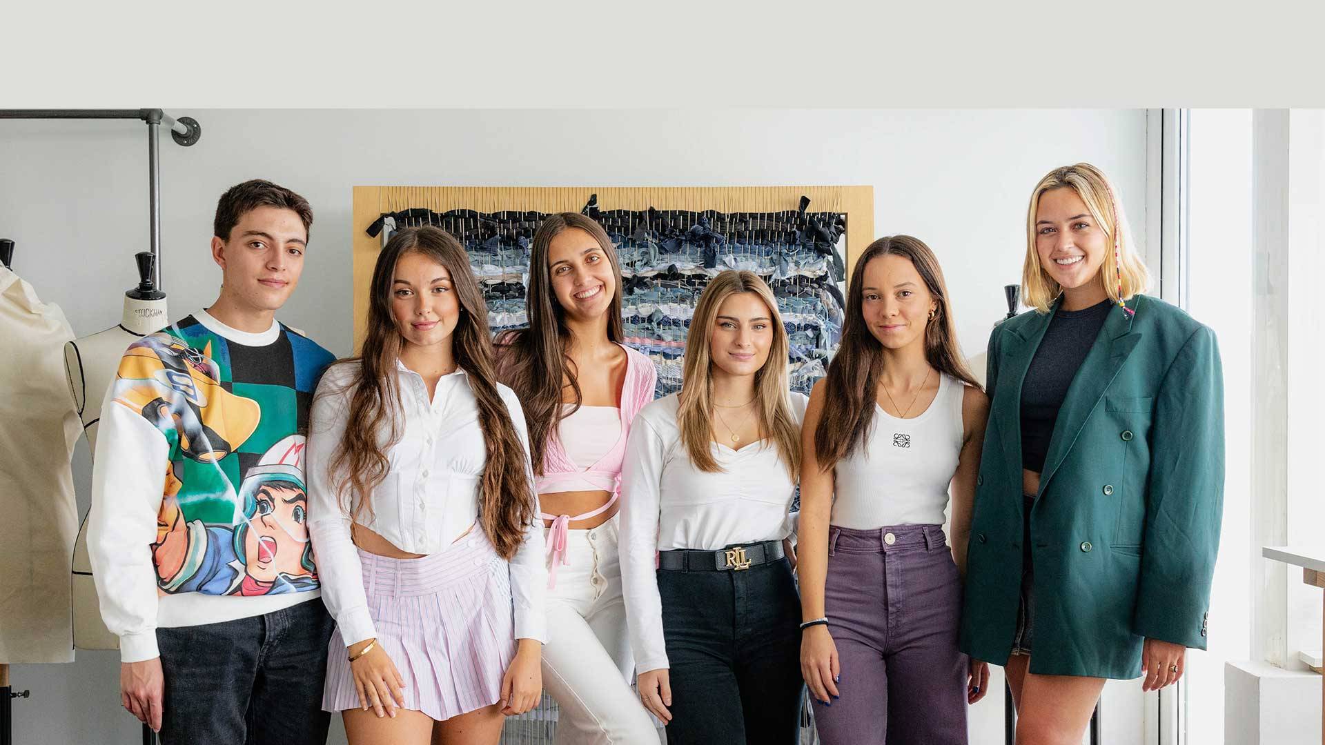 Un grupo de seis jóvenes posan en un estudio de moda con ropa moderna y sonrisas.