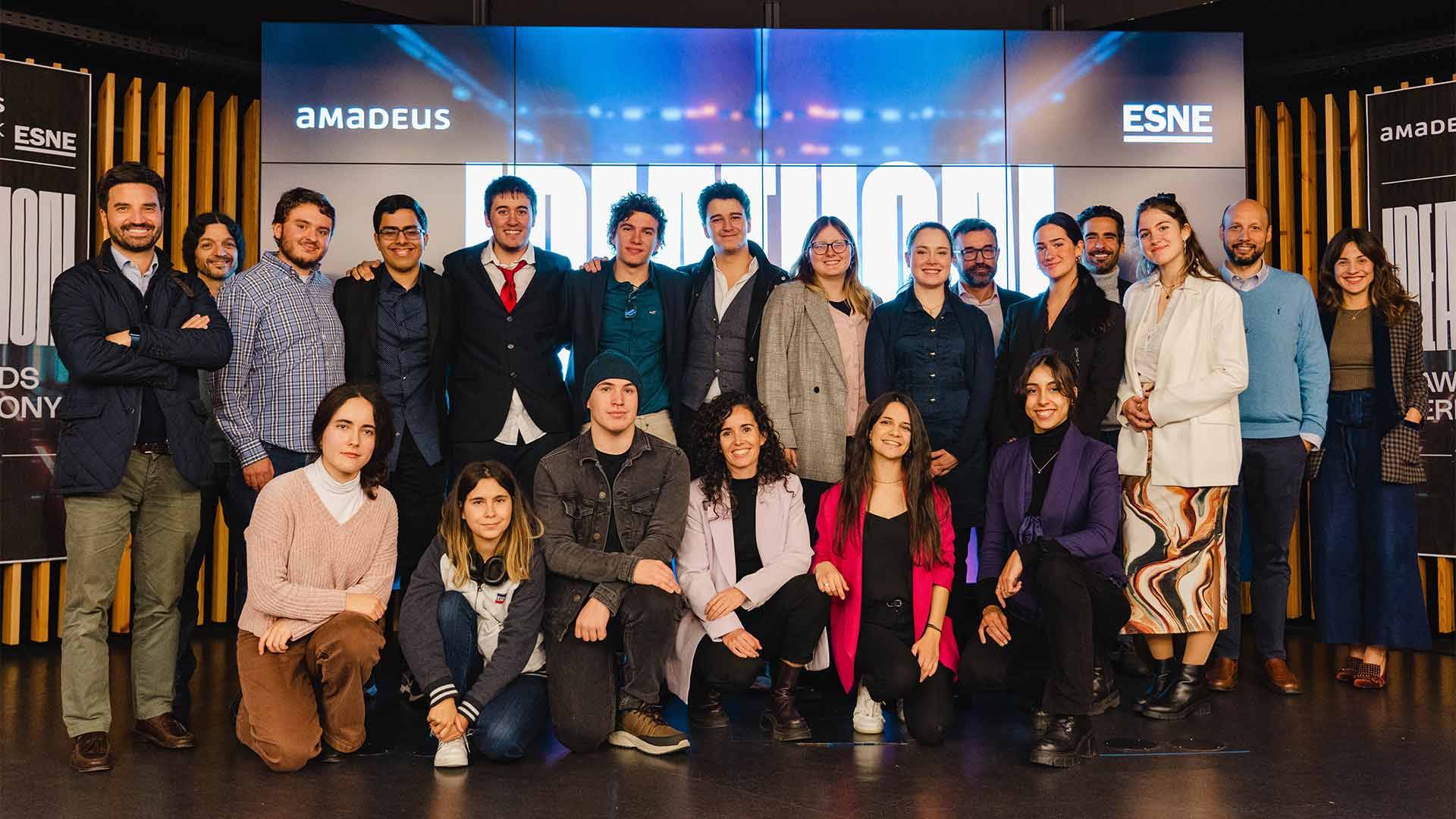 Un grupo de personas sonrientes posando en un evento con pantallas de fondo.