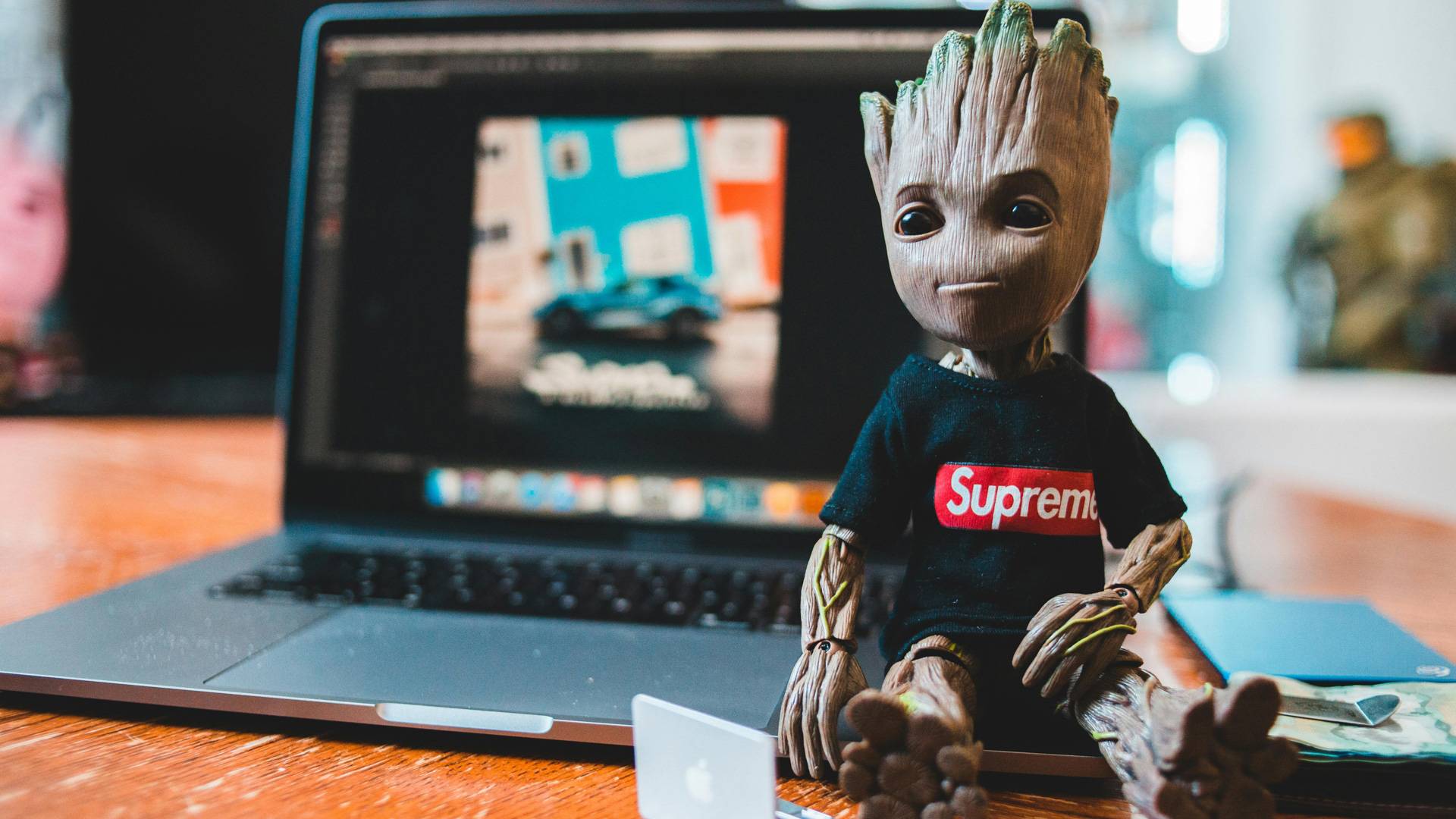 Una figura de Groot sentado frente a una computadora portátil con una pantalla que muestra una imagen de fondo.