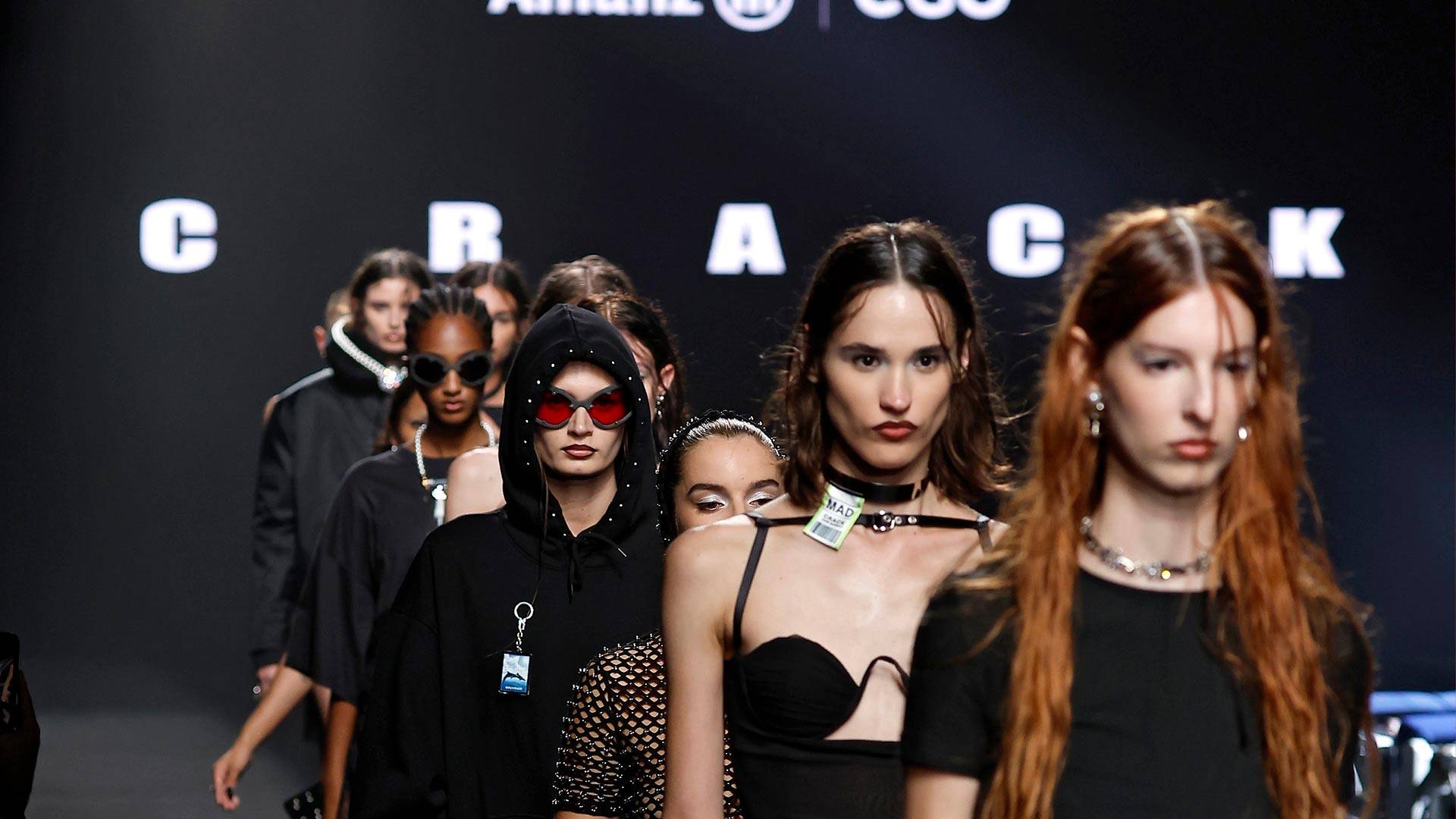 Un grupo de modelos desfilando en una pasarela de moda con diversas prendas de vestir y accesorios.