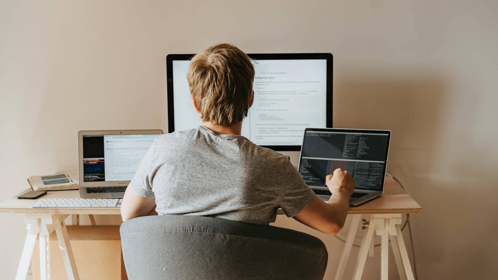 Una persona está trabajando en múltiples computadoras en un escritorio.