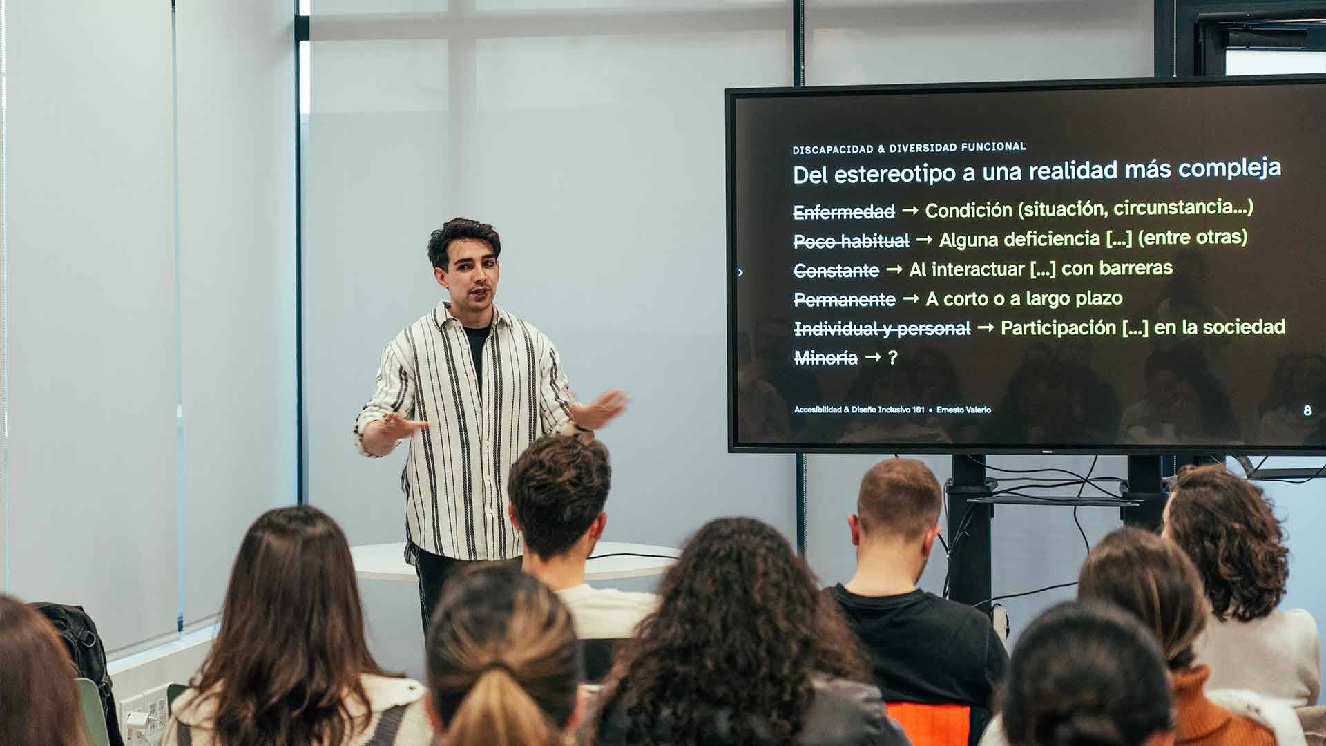 Una persona está dando una charla sobre estereotipos y diversidad funcional ante un público atento.