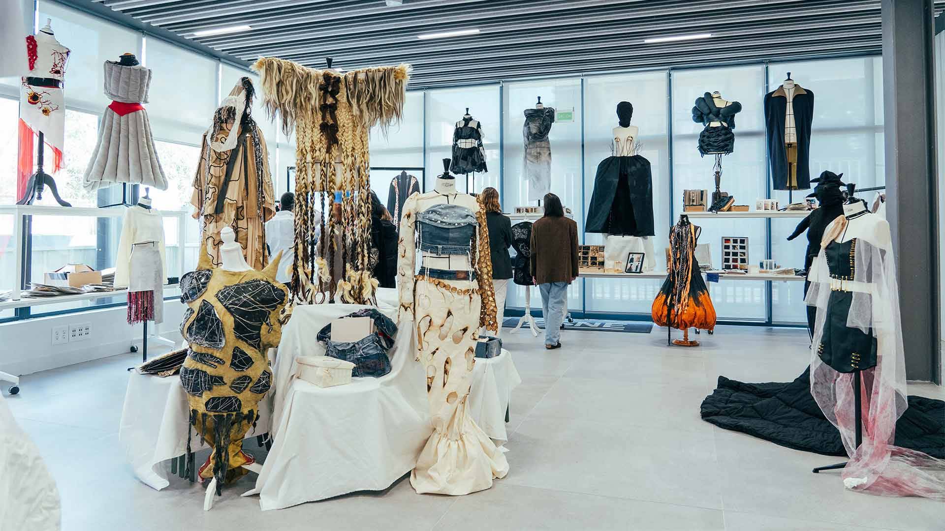 La imagen muestra una exposición de moda contemporánea con diversas prendas y diseños exhibidos en un espacio moderno.
