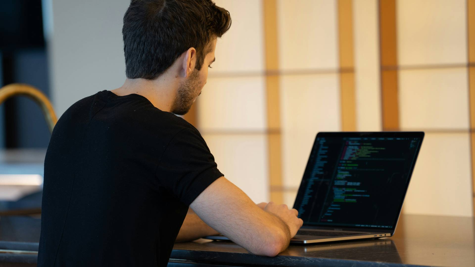 Un joven trabaja en su computadora portátil en un ambiente moderno.