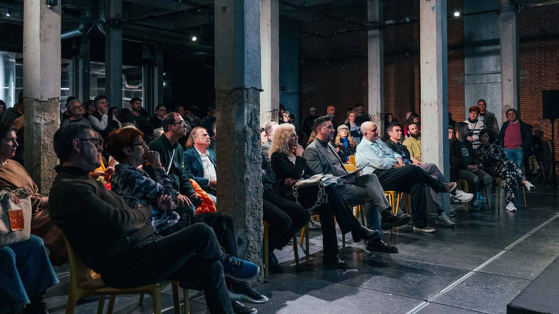 Un grupo de personas sentadas en un auditorio durante un evento.