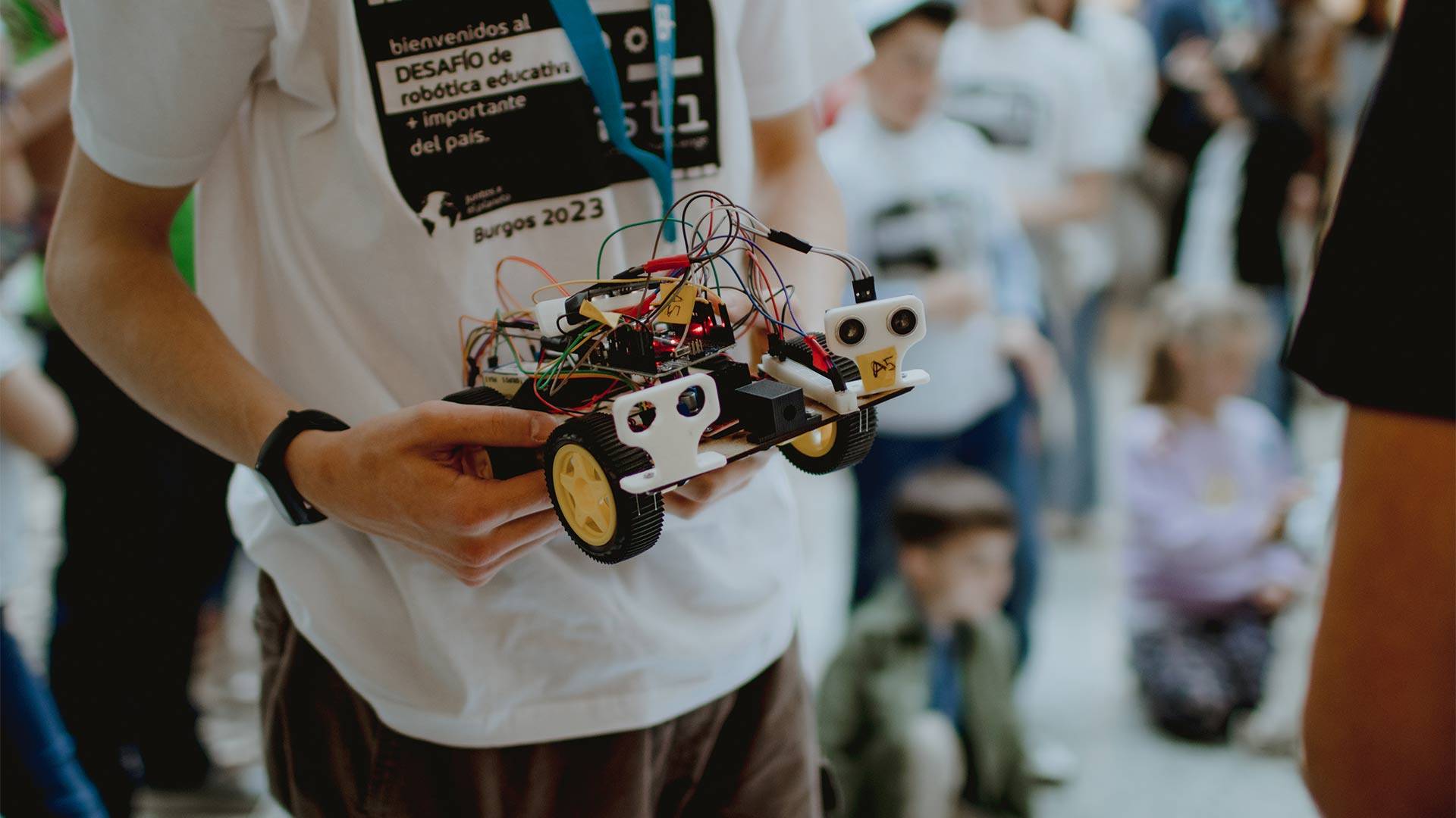 Un participante sostiene un robot en un evento de robótica educativa.