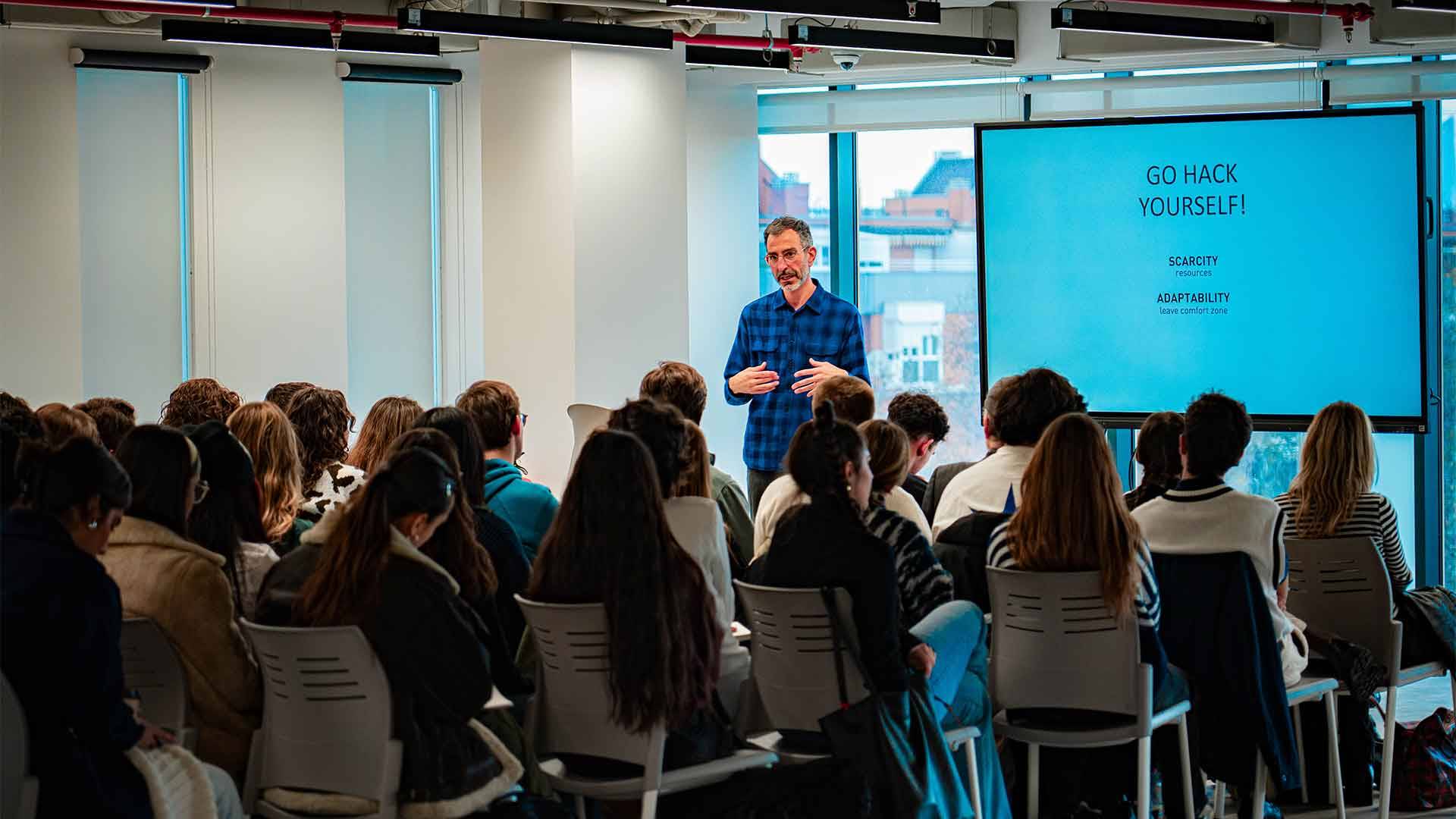 Una presentación en un salón con un público atento escuchando a un orador.