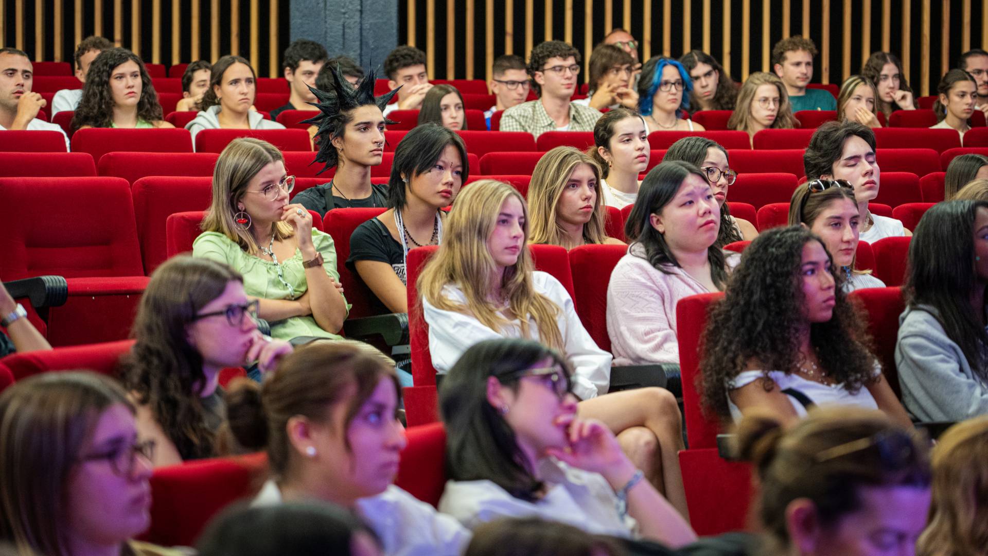 Un grupo de jóvenes escuchando atentamente en un auditorio.