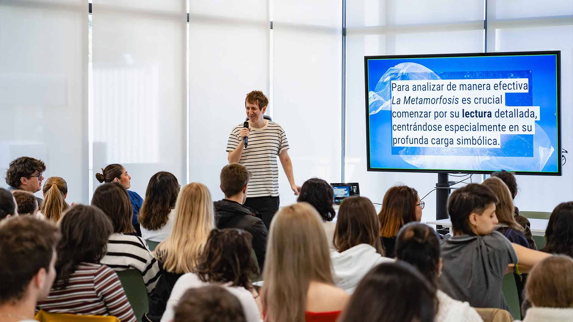 Un presentador expone ante un público sobre la obra 'La Metamorfosis'.