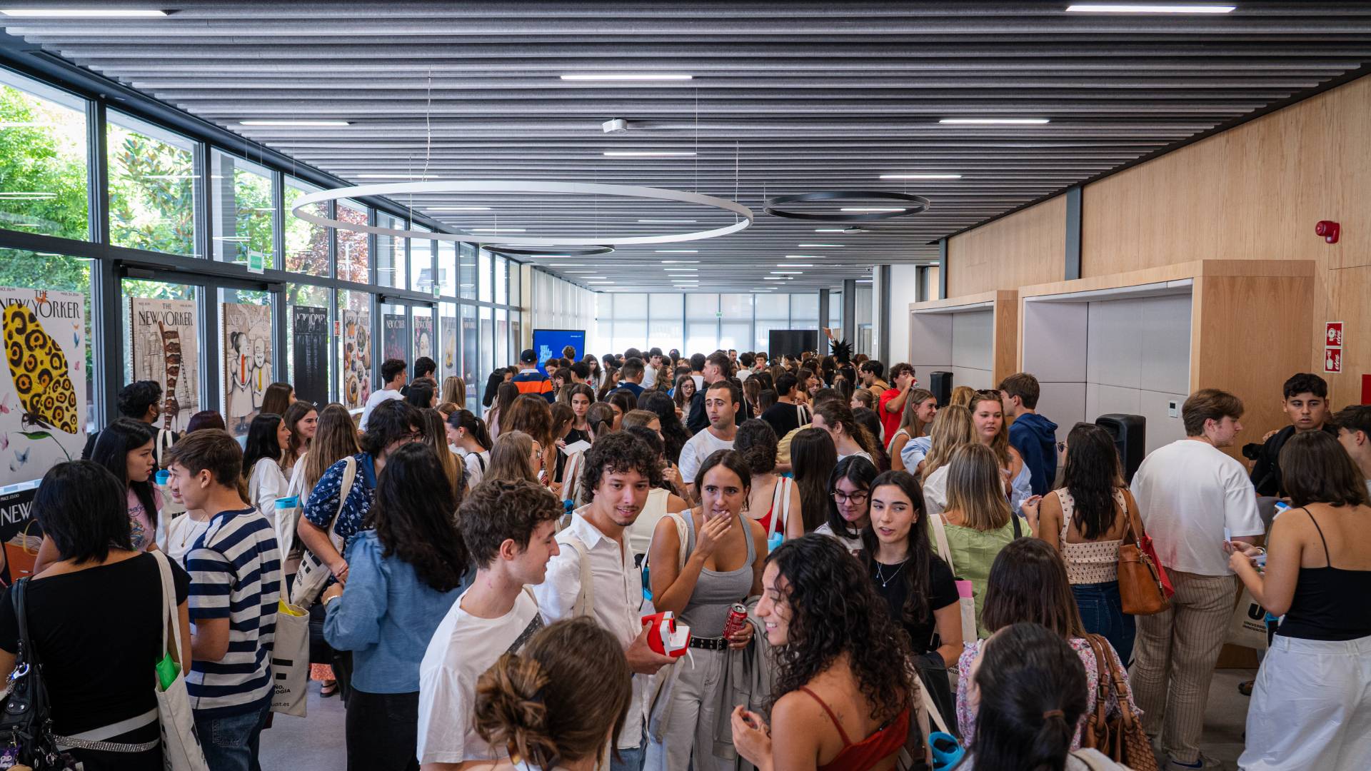Una gran multitud de personas socializando en un espacio interior luminoso.