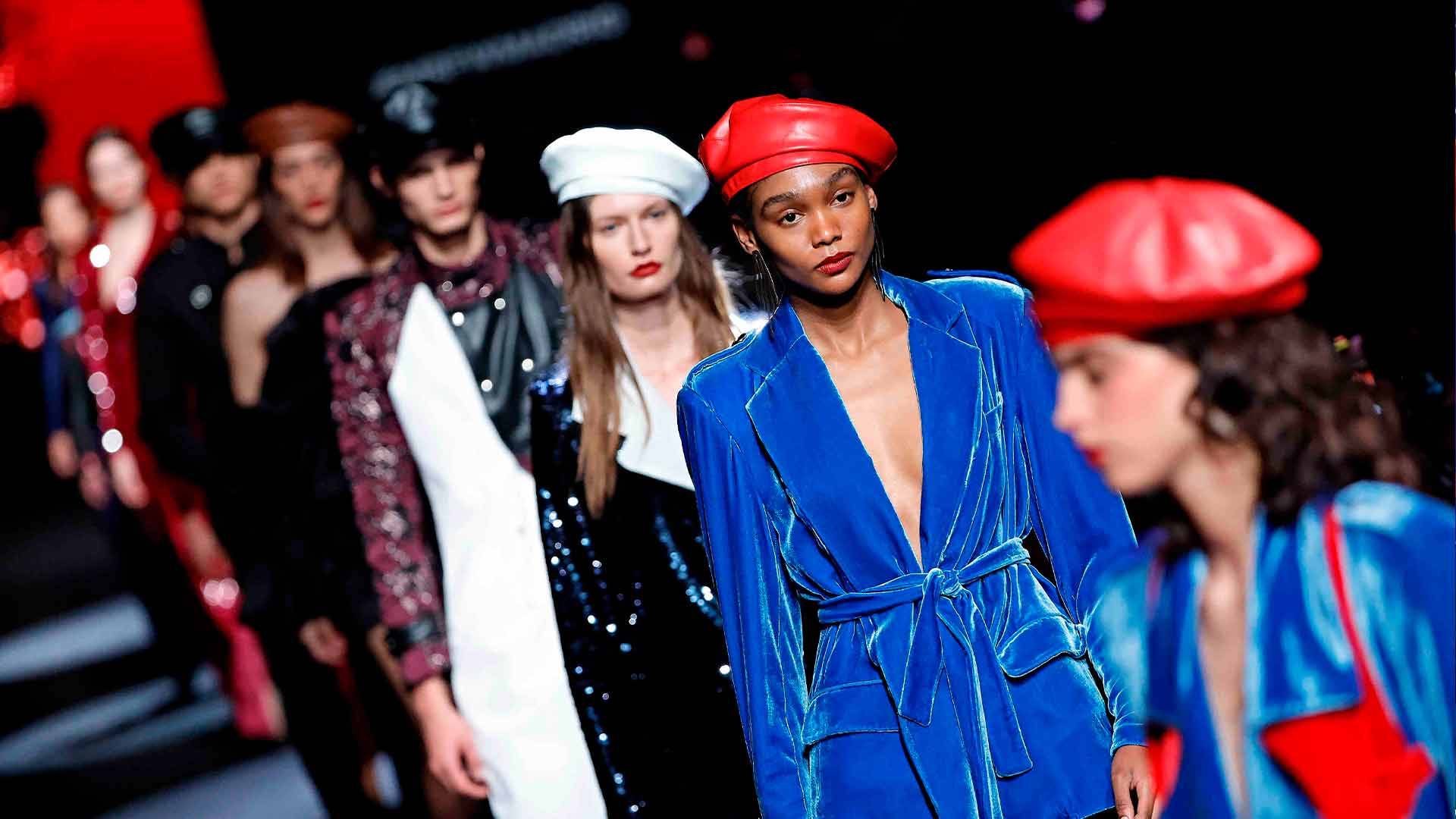 Un grupo de modelos desfilando en una pasarela de moda con diferentes estilos de vestimenta y tocados.
