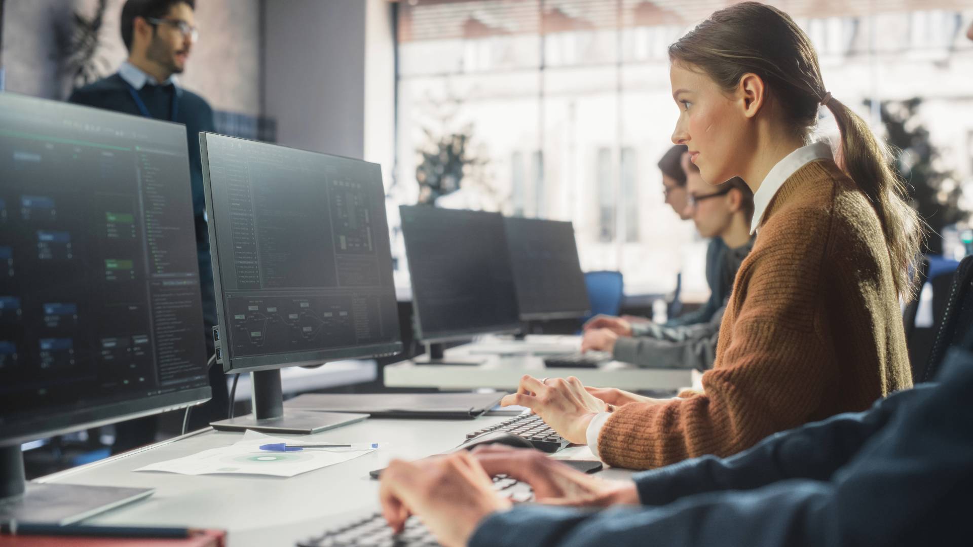 Un grupo de personas trabaja en sus computadoras en una oficina moderna.