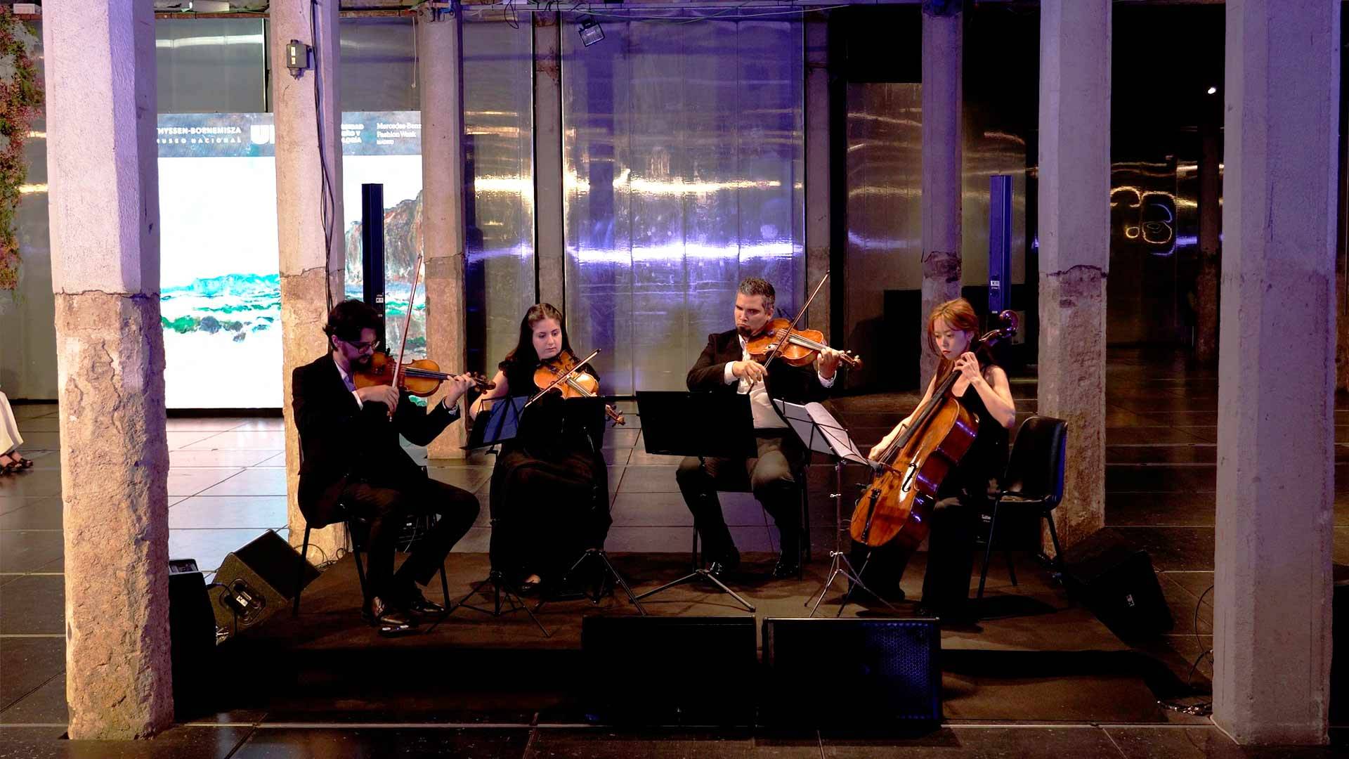Un cuarteto de música clásica interpreta una pieza en un espacio moderno y elegante.
