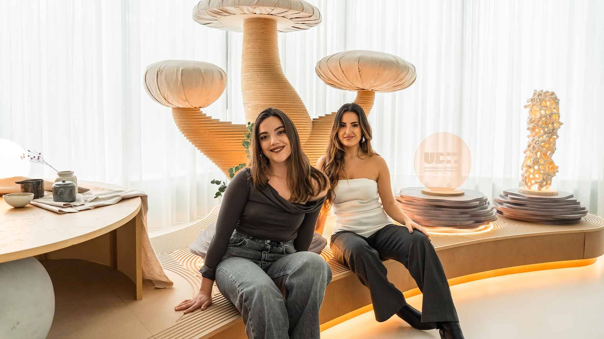 Dos mujeres posan sonrientes en un entorno moderno con decoración de setas de diseño.