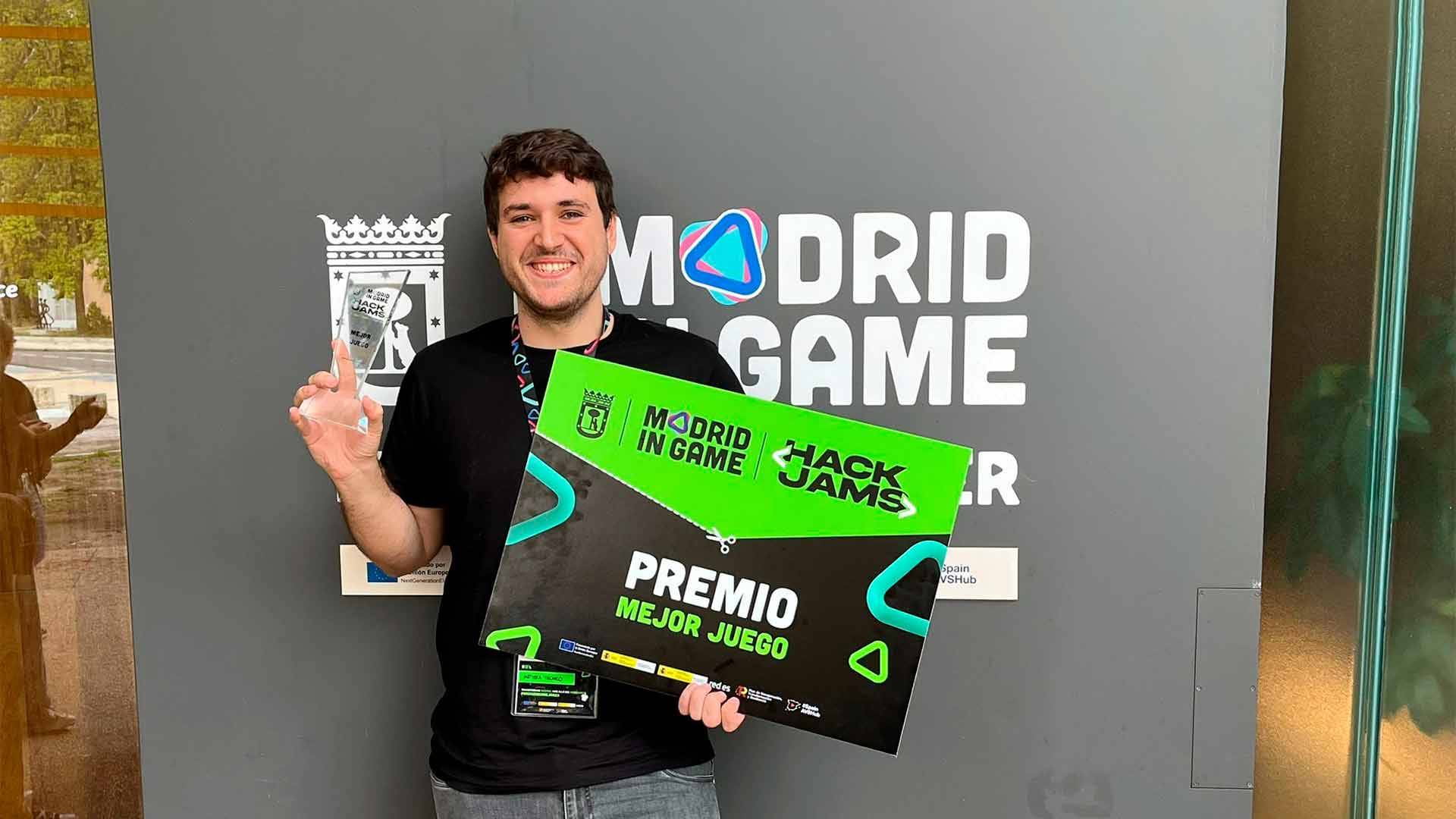 Una persona sostiene un trofeo y un cartel que indica que ha ganado el premio al mejor juego en un evento de videojuegos.