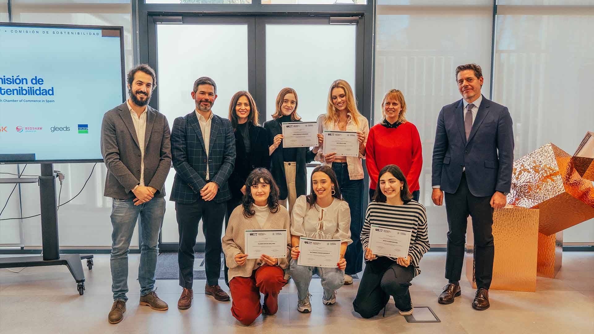 Un grupo de personas sonrientes posan con certificados en un evento de graduación.