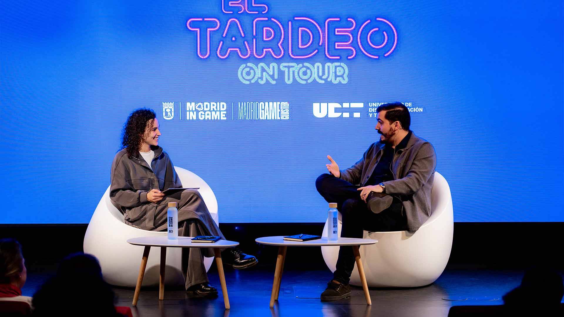 Dos personas conversando en un evento sobre 'El Tardeo'.