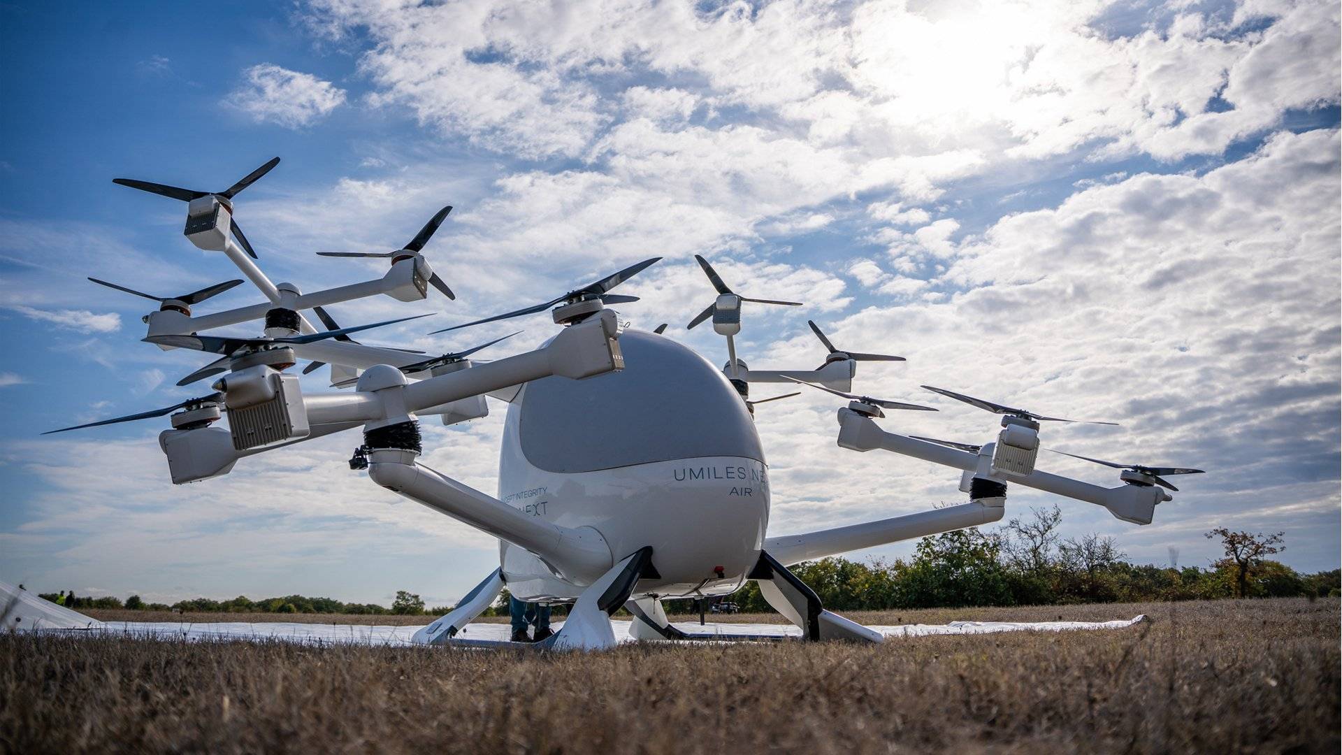 Un dron de diseño futurista estacionado sobre un campo despejado bajo un cielo nuboso.