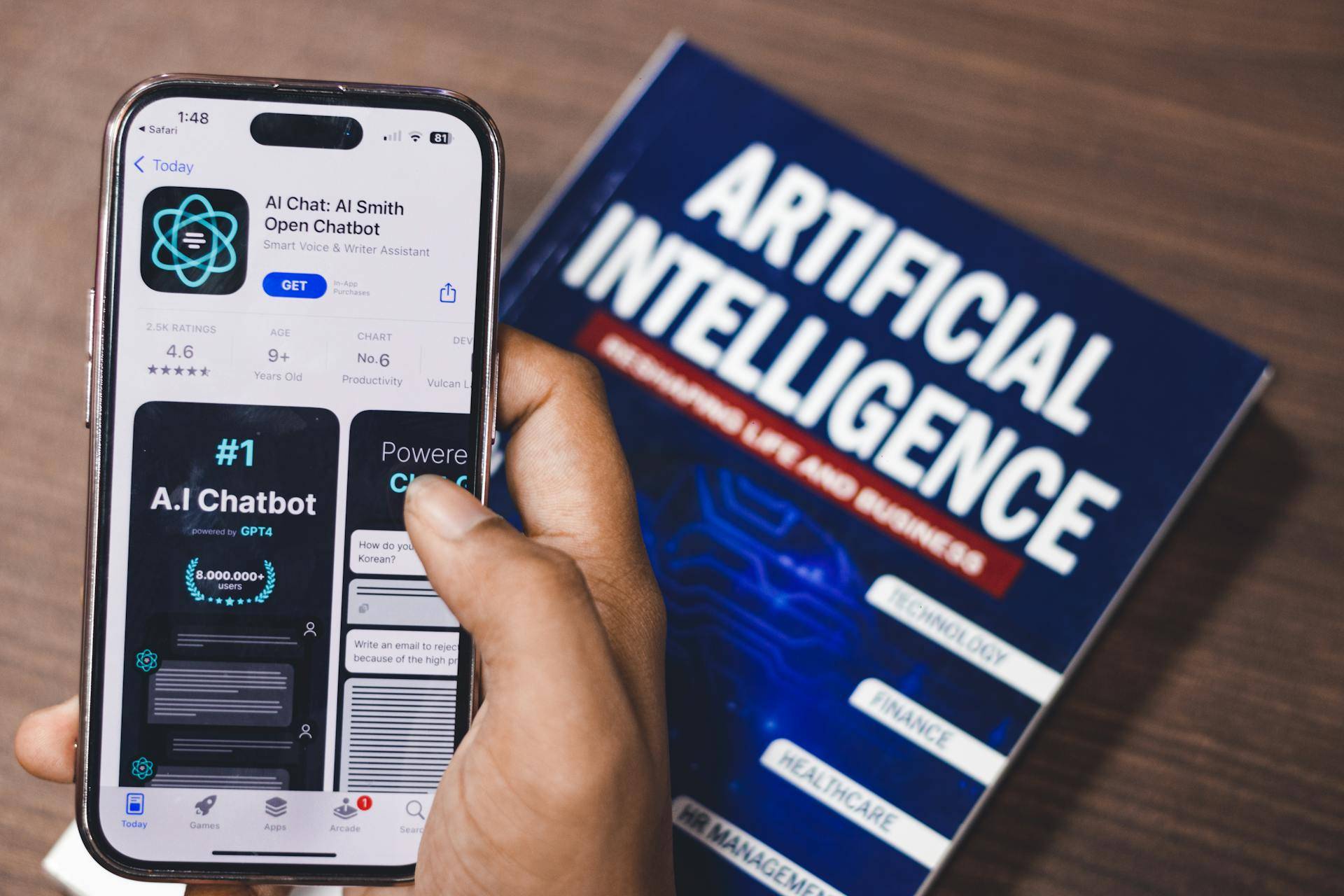 Una persona sostiene un teléfono móvil que muestra una aplicación de chatbot junto a un libro sobre inteligencia artificial.