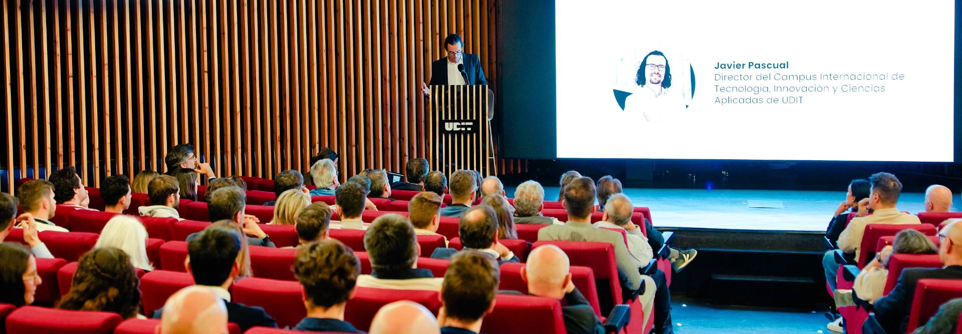 Un conferencista presenta en un auditorio frente a una audiencia atenta.
