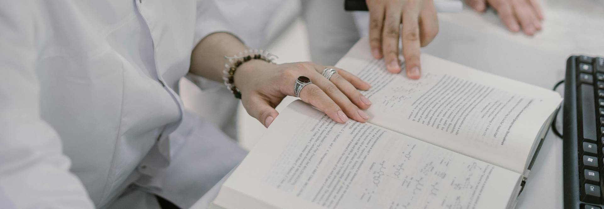 Dos personas revisan un libro de texto en un entorno de estudio.