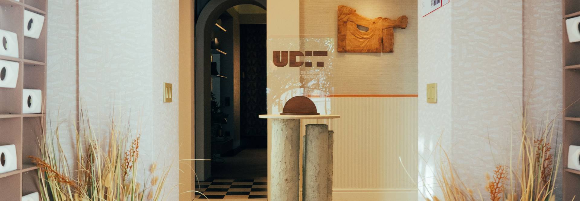 La imagen muestra un interior elegante con un mostrador y decoraciones minimalistas en tonos claros.