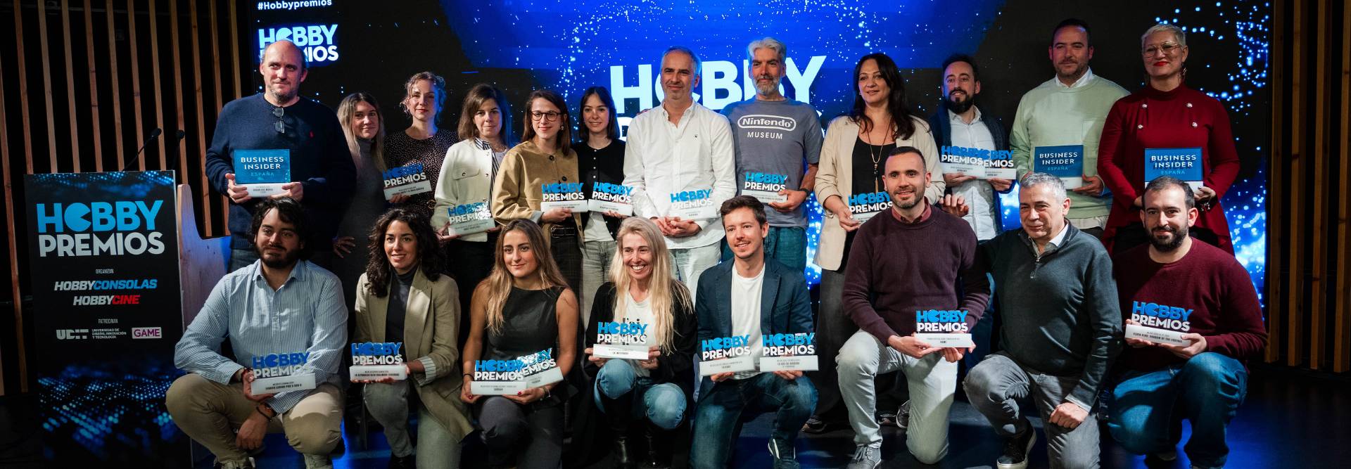 Un grupo de personas sostiene premios en un evento relacionado con hobbies.