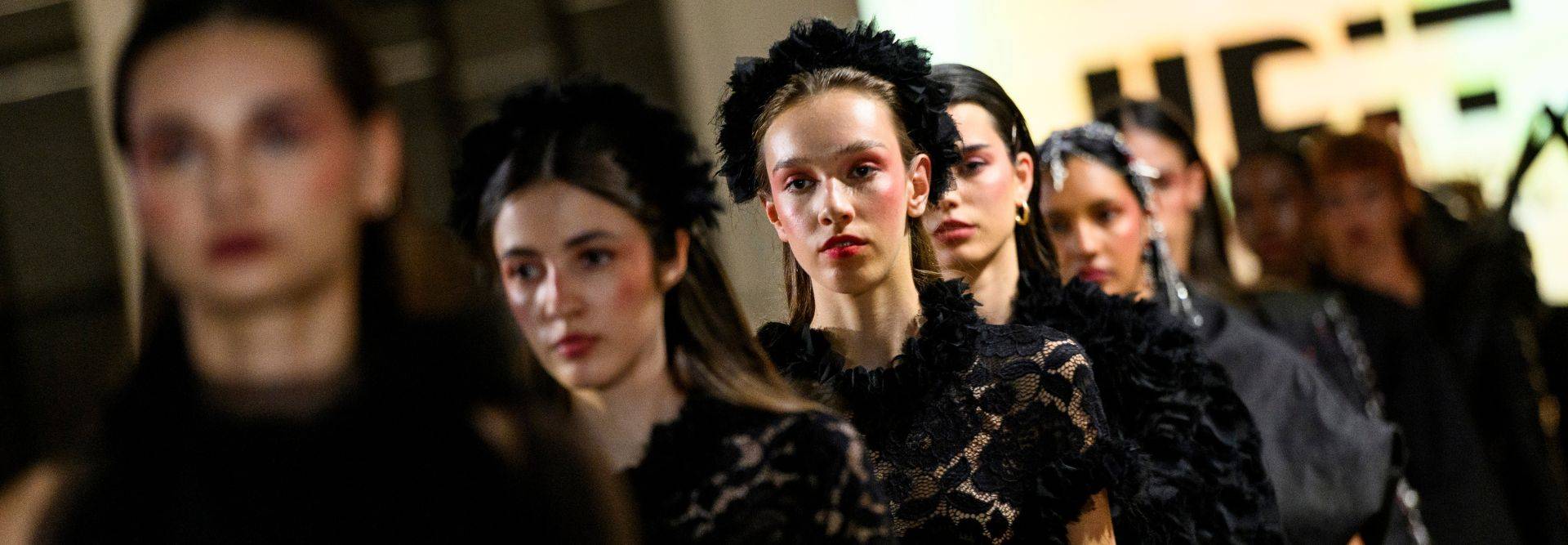 Desfile de modelos con vestidos negros y detalles elegantes.
