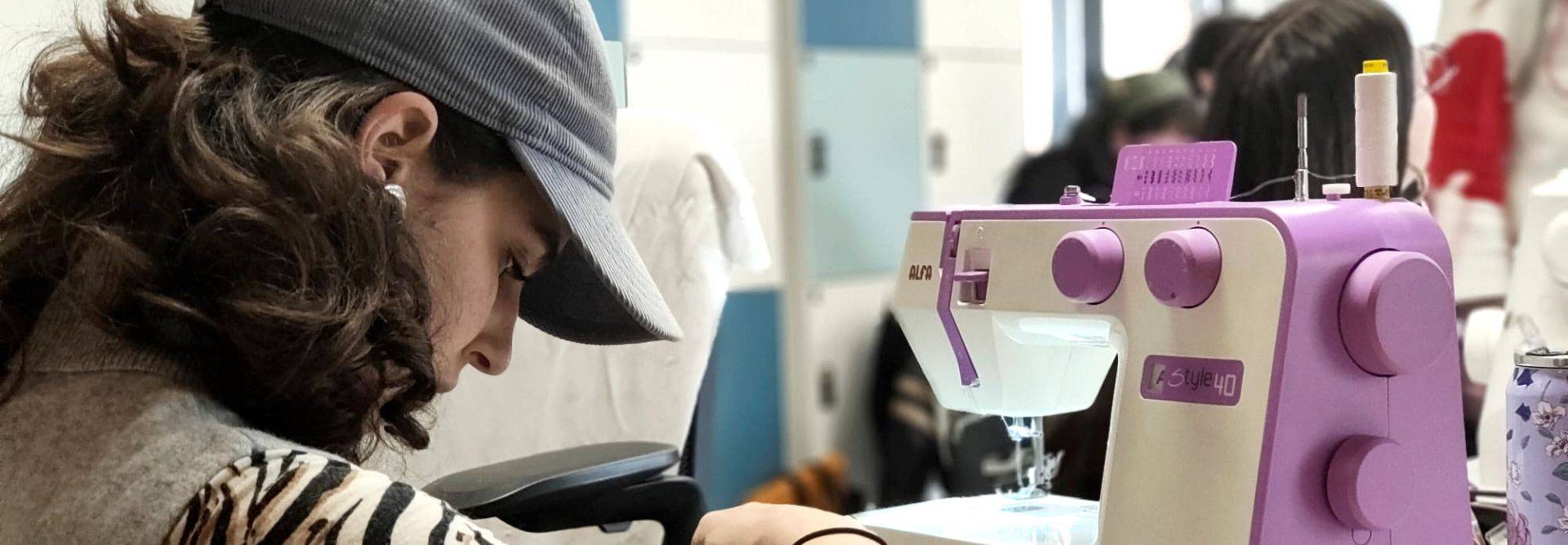 Una persona está cosiendo con una máquina de coser de color morado y blanco.