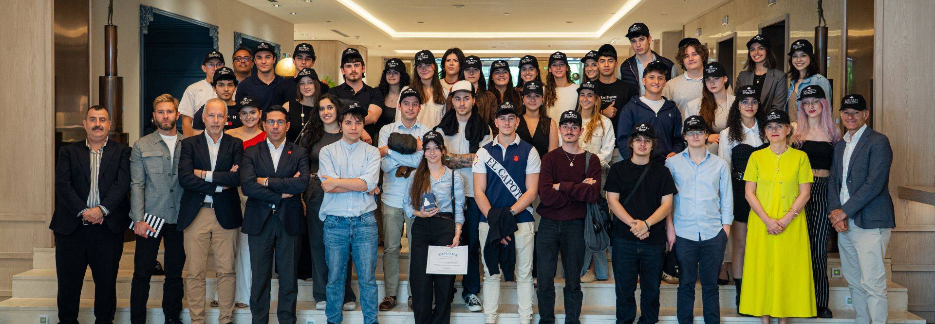 Un grupo de personas posando en una escalera con gorros y miradas alegres.