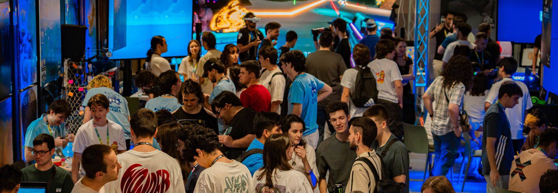 Una gran multitud de personas interactúa en un evento lleno de energía y tecnología.