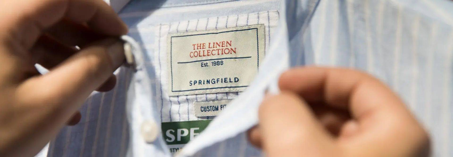 Una persona sostiene la etiqueta de una camisa de la colección de lino de Springfield.