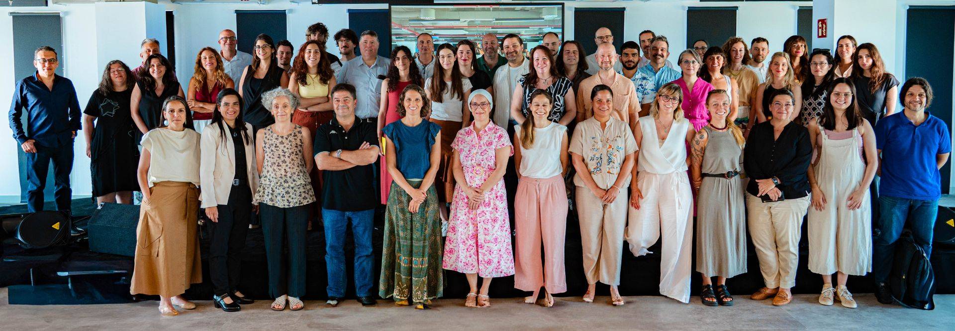 Un grupo grande de personas posando juntas en un entorno luminoso.