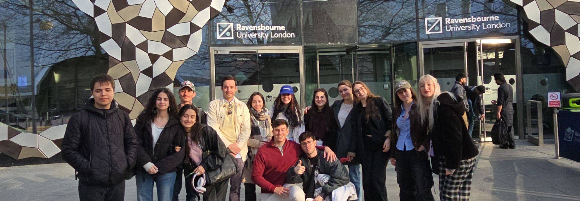 Un grupo de personas posando frente a la entrada de la Universidad Ravensbourne en Londres.