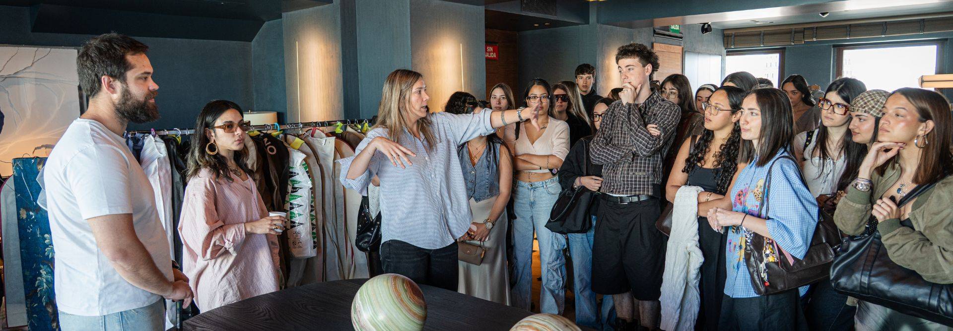Un grupo de personas observa a una mujer que está explicando algo en un evento o reunión.