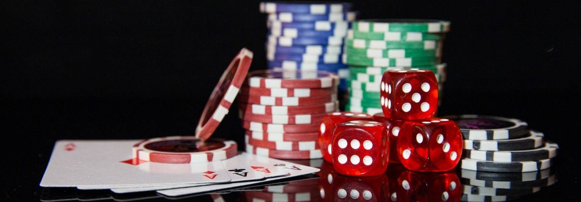 La imagen muestra fichas de póker y dados sobre una mesa de juego.